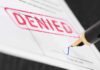 Denied stamp on a document with pen.