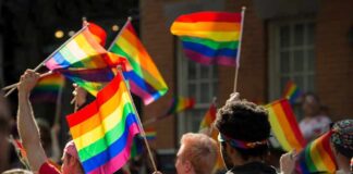 People holding rainbow flags at an outdoor gathering