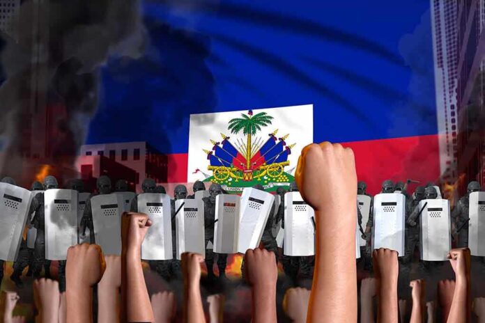 a crowd of raised fists against the flag of Haiti in the background