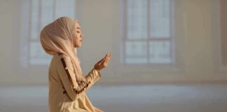 Woman praying indoors on a prayer mat.