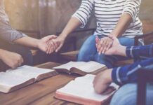 Group holding hands over open books