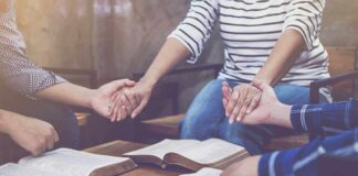 Group holding hands over open books