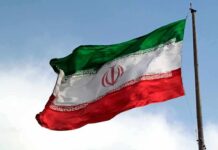 Iranian flag waving against a blue sky.