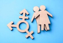 Wooden transgender symbol and couple figures on blue background