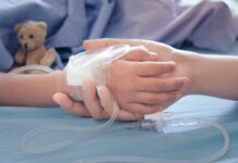 Childs hand with IV held by adult