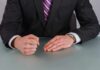 Person in suit with clenched fist on table