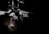 Person holding a firearm in the dark background