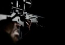 Person holding a firearm in the dark background