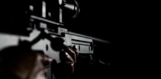 Person holding a firearm in the dark background