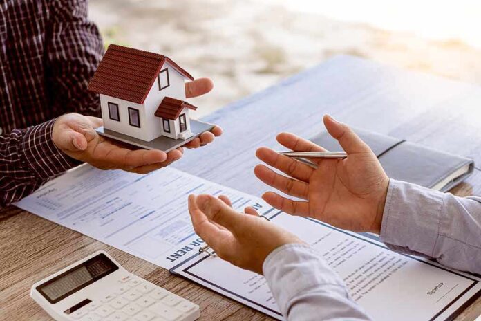 Two people discussing real estate contract with model house