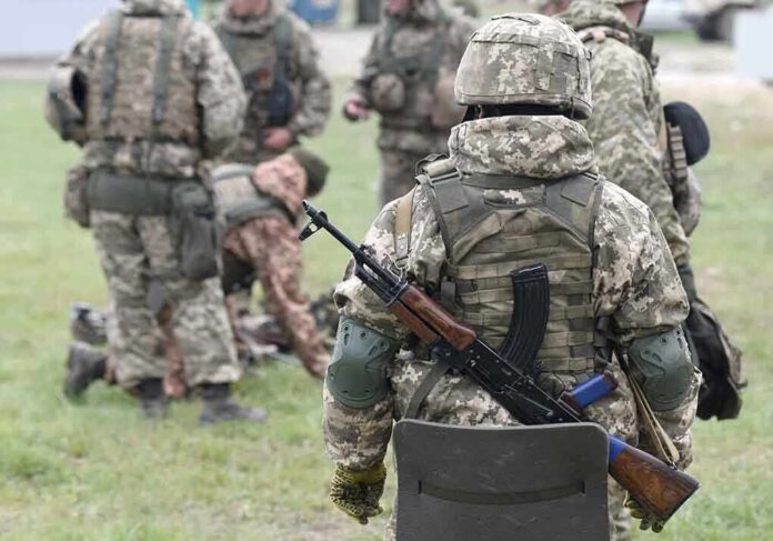 Soldiers in camouflage gear gathered on grass field