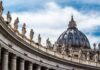 St. Peter's Basilica dome with statues and clouds.