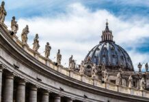 St. Peter's Basilica dome with statues and clouds.