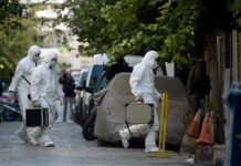 Investigators in hazmat suits carrying equipment cases