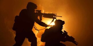 Two soldiers with weapons silhouetted against fiery background