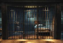 Empty prison cell with metal bars and bed