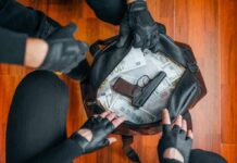 Gloved hands around bag with money and gun