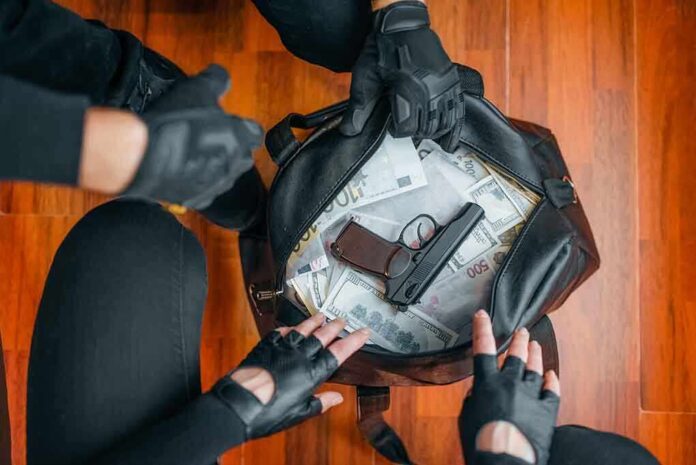 Gloved hands around bag with money and gun