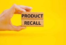 Hand holding Product Recall blocks on yellow background