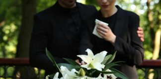 Mourners in black holding white flowers at funeral