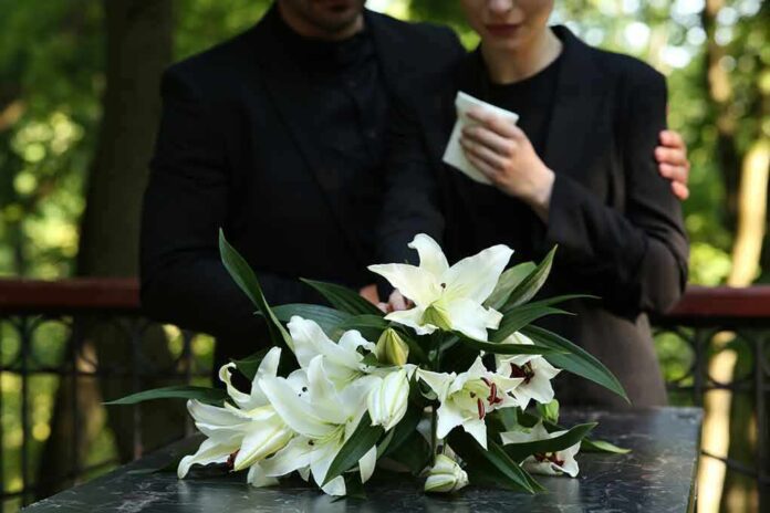 Mourners in black holding white flowers at funeral