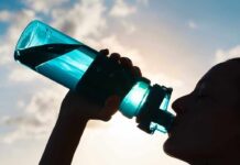 Silhouette of person drinking from a water bottle