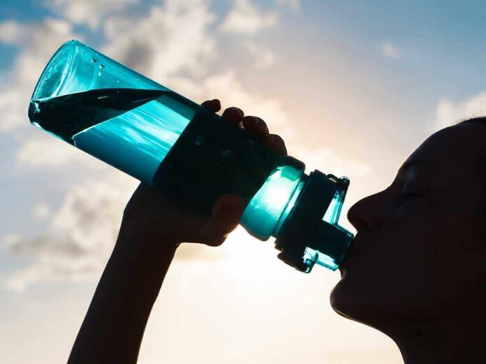 Silhouette of person drinking from a water bottle