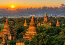 Sunset over ancient temple complex with lush greenery