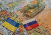 Toy tank on map with Ukraine and Russia flags