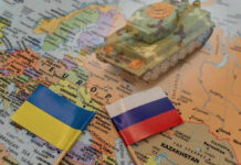 Toy tank on map with Ukraine and Russia flags