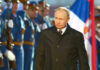 A man in dark coat at a military event