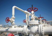 Industrial pipeline with red valves against a clear blue sky