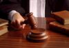 A judges hand holding a gavel over a wooden desk with law books
