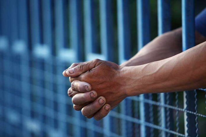 Close-up of clasped hands resting on a blue fence