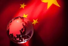 A globe illuminated against the backdrop of the Chinese flag