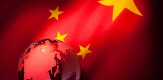 A globe illuminated against the backdrop of the Chinese flag