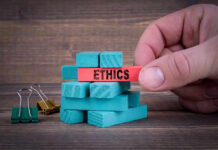 Hand holding red block labeled ETHICS above blue blocks.