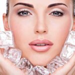 Close up of a woman holding ice cubes around her face