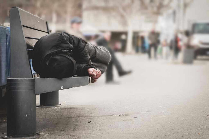 1016111287 Person sleeping on a bench in a public area.