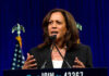 Woman speaking behind a podium with blue backdrop.