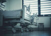 Empty hospital beds by a window.
