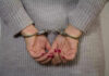 Person in handcuffs with gray sweater.