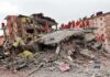 Rescue workers in orange uniforms on a collapsed building site after an earthquake