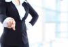A professional woman in a suit pointing with her right hand