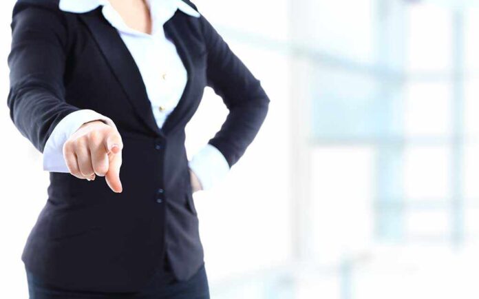 A professional woman in a suit pointing with her right hand