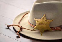 A sheriffs hat with a vintage badge resting on a wooden surface
