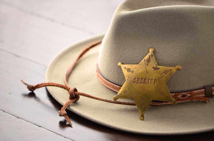 A sheriffs hat with a vintage badge resting on a wooden surface