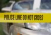 Yellow police tape reading POLICE LINE DO NOT CROSS in front of a vehicle