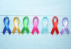Colorful awareness ribbons on light wooden background.