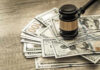 Stacey Abrams — Slapped With Record Breaking Ethics Fine Gavel on a pile of hundred-dollar bills.